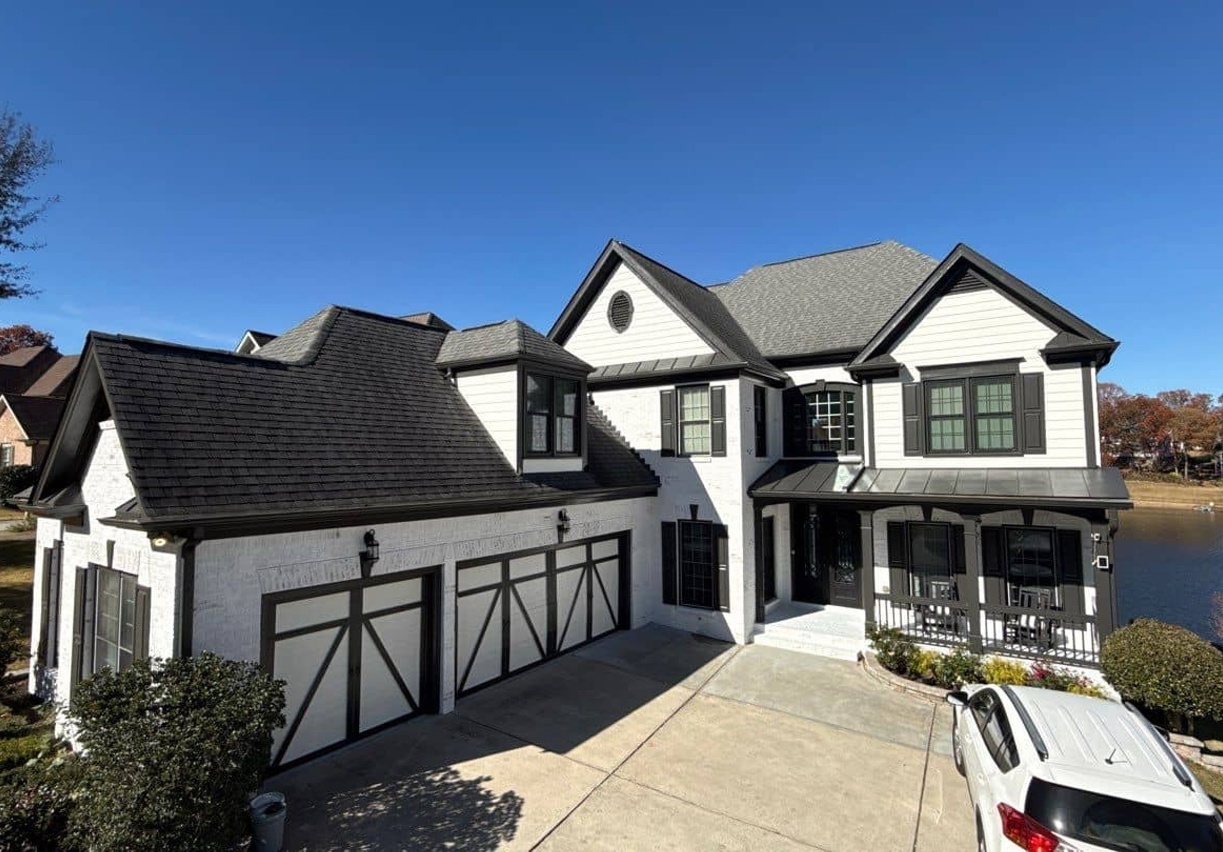 Freshly painted two-story home with white exterior and black accents beside a lake