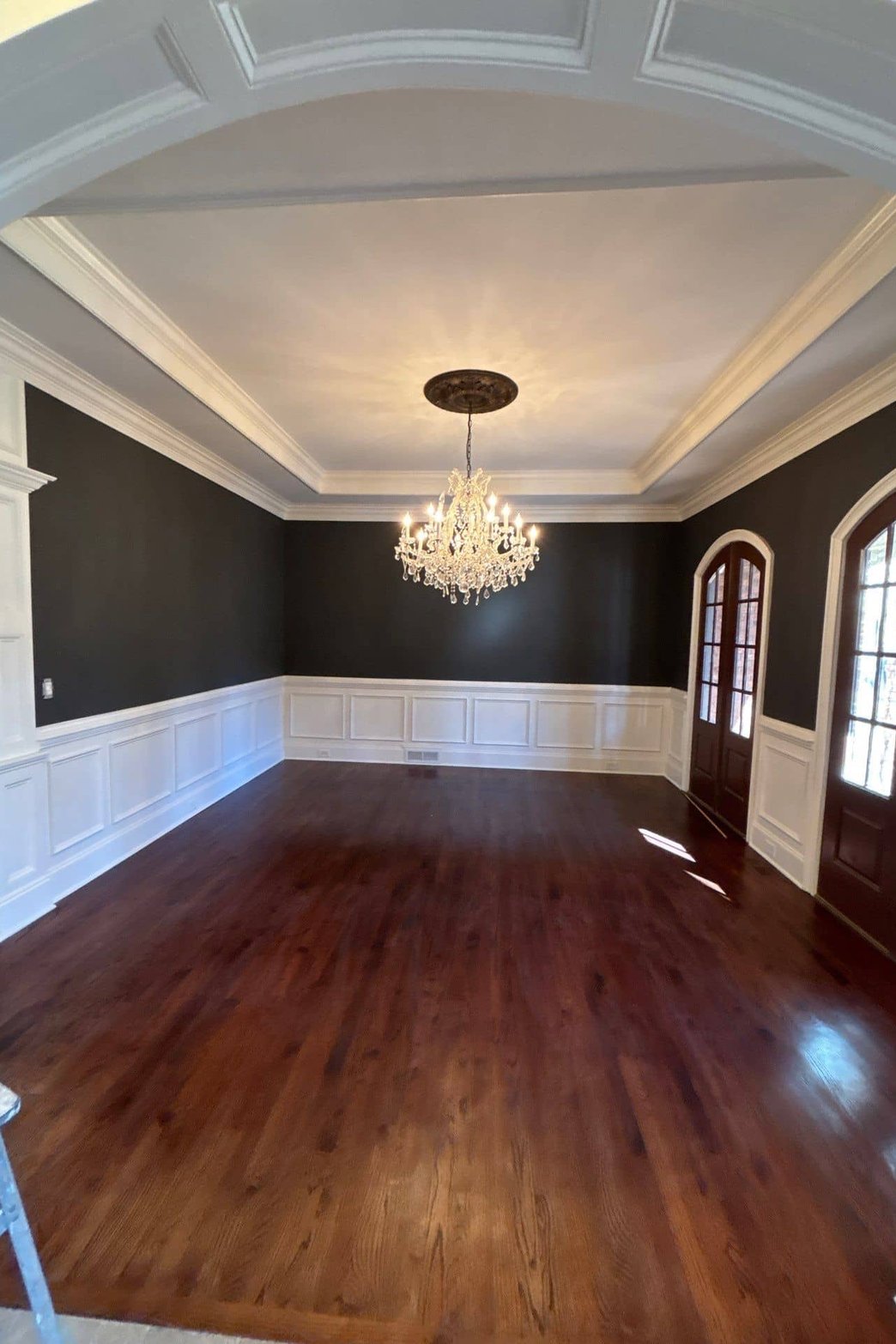 Freshly painted dining room with dark walls, white wainscoting, and chandelier